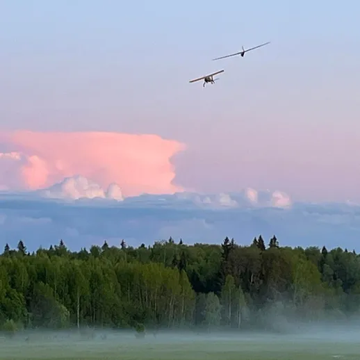 Два самолета в полете над лесом на фоне красивого заката в конце летнего вечера