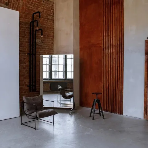 Современный интерьер с зеркалом и стульями в пространстве с кирпичными стенами