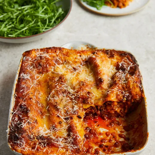 Вкусная лазанья с мясом и соусом, поданная с салатом из свежих овощей в уютной кухне