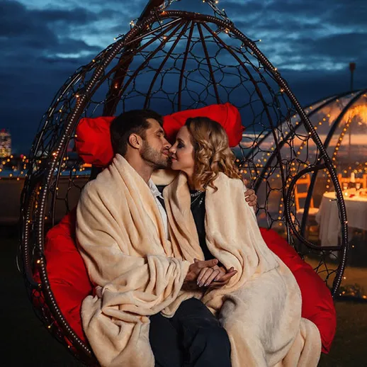 Романтический вечер на крыше в уютном кресле-качалке с огоньками в ночном небе