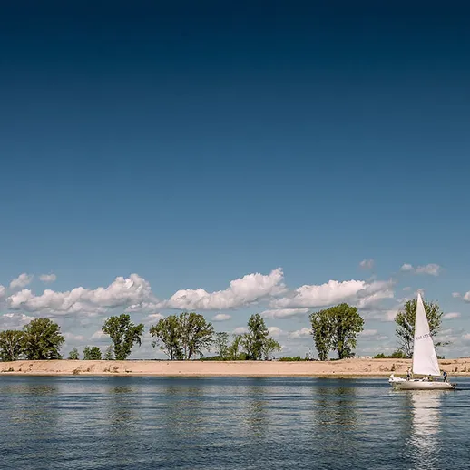 Парусная лодка на спокойной воде реки под ясным небом весной
