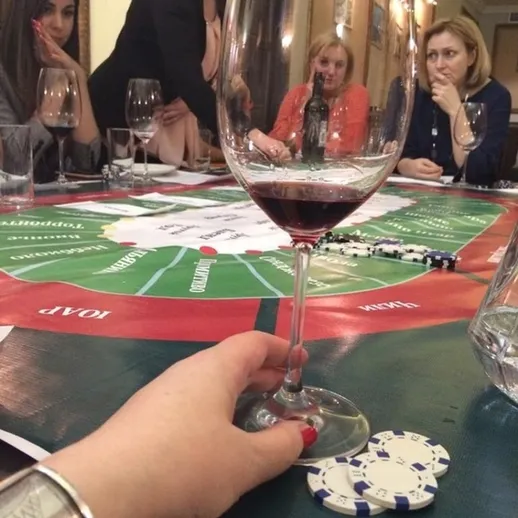 Игроки наслаждаются вечеринкой с покером и красным вином в уютной комнате ресторана