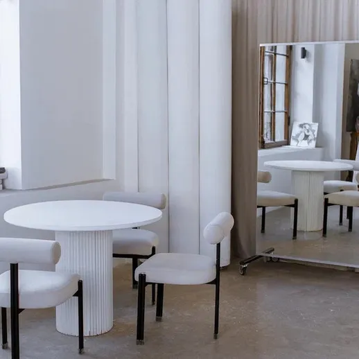 Современный минималистский интерьер с круглым столом и зеркальной панелью в светлом помещении