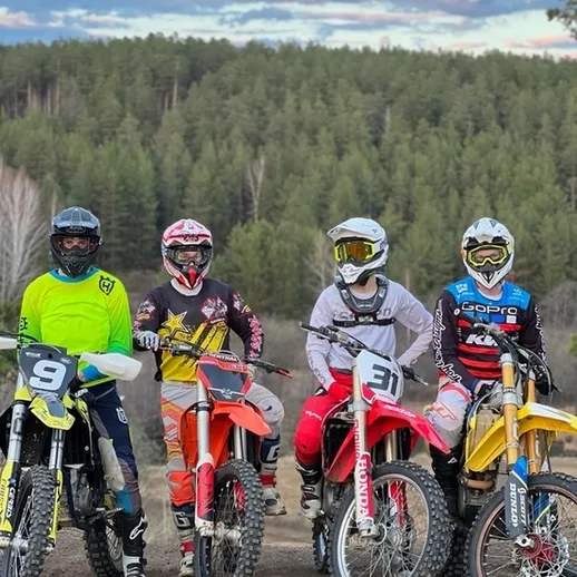 Четыре мотоциклиста на внедорожниках в лесу во время заката