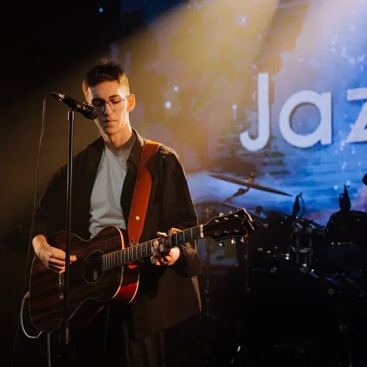 Концерт музыкального исполнителя на сцене в джазовом клубе ночью