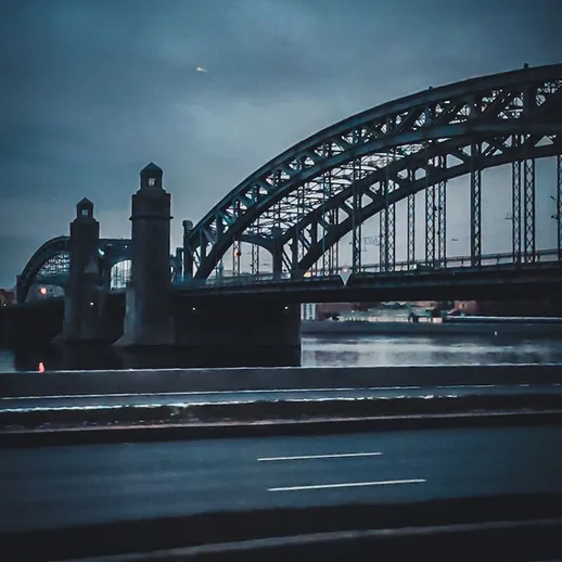 Мост через реку с красивой архитектурой на фоне серого неба в вечернее время