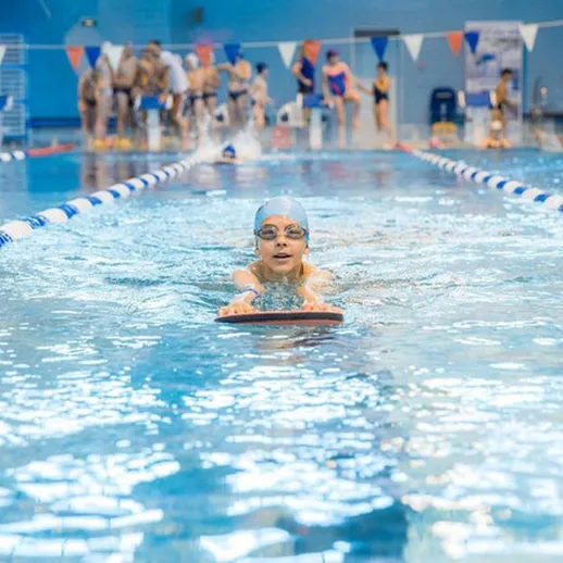 Дети учатся плавать в спортивном бассейне, совершенствуя техники в ясный день для подготовки к соревнованиям