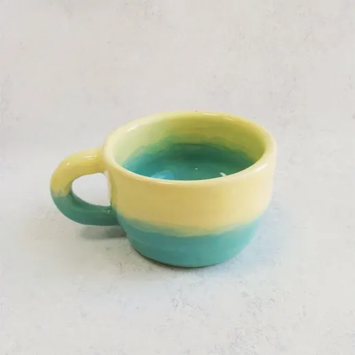 Яркая керамическая чашка с зелёно-желтой рябью, сидящая на нейтральном фоне в интерьере