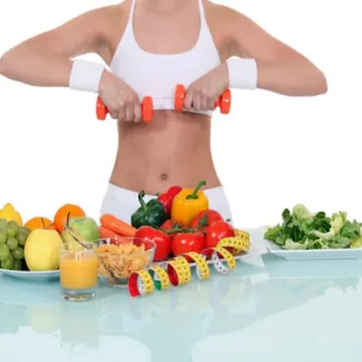 Женщина занимается спортом с гантелями на фоне свежих овощей и фруктов в светлом помещении