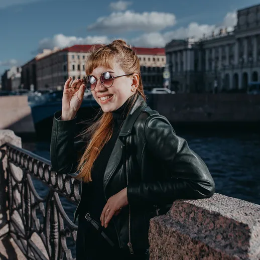 Молодая женщина в солнечных очках на набережной реки в Санкт-Петербурге наслаждается теплым днем