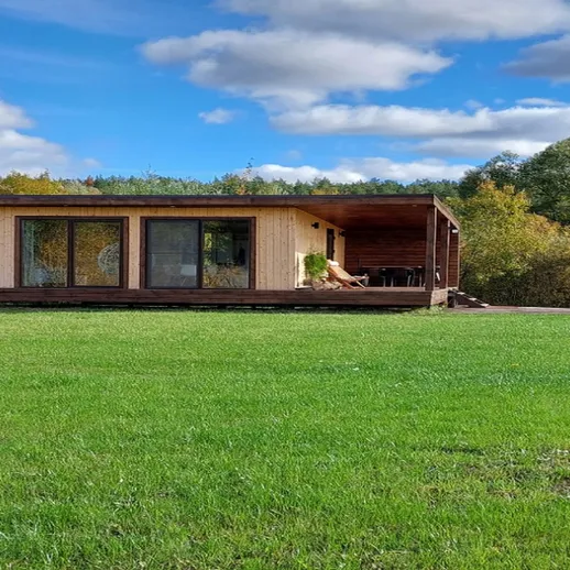 Уютный деревянный дом на фоне зелёного луга в солнечный день на природе