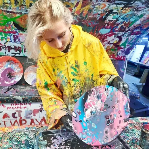 Молодая художница создает абстрактное искусство с яркими цветами в своей студии