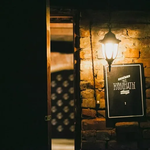 Старинный светильник у двери с вывеской Кофейня на кирпичной стене в уютном кафе