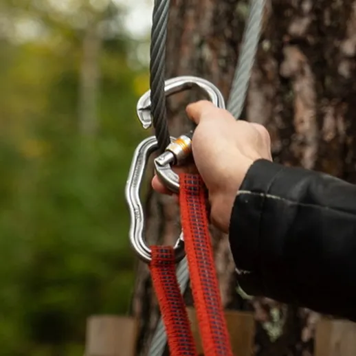 Установка карабина на канат при подготовке к скалолазанию на природе в лесу осенью