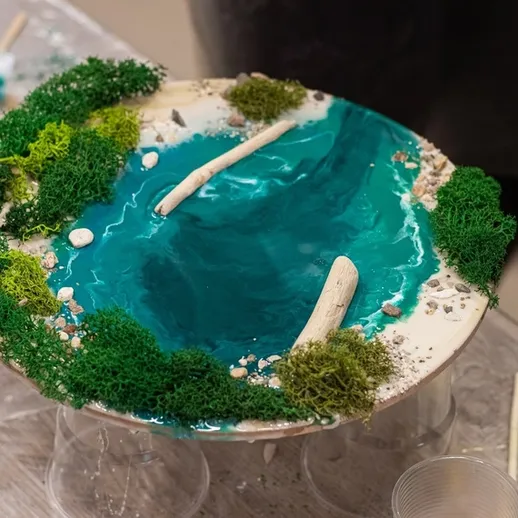 Миниатюрный ландшафт с озером и зелеными растениями, созданный мастерами на выставке в июле