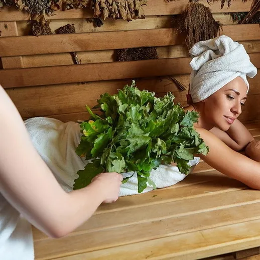Женщина в сауне, отдыхающая с травами, расслабляясь после долгого трудового дня на природу