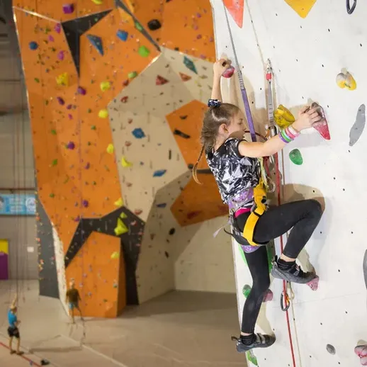 Подъемная стенка для скалолазания в спортивном зале с молодыми спортсменами