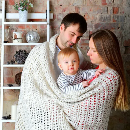 Счастливая семья согревается под теплым пледом в уютной квартире с кирпичными стенами