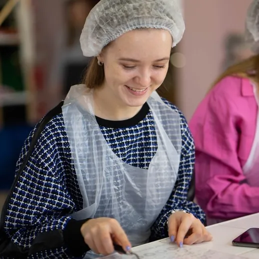 Девушка занимается творческой работой в мастерской, улыбается и сосредоточена на процессе