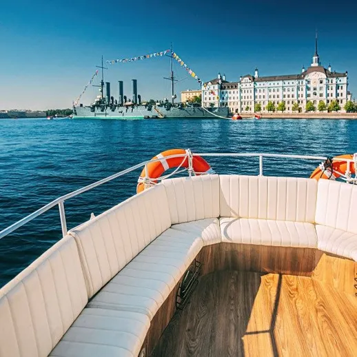 Корабль на воде и уютная лодка с белыми сиденьями на фоне исторического здания