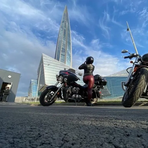 Мотоциклистка на фоне зданий Санкт-Петербурга наслаждается прекрасным весенним днем