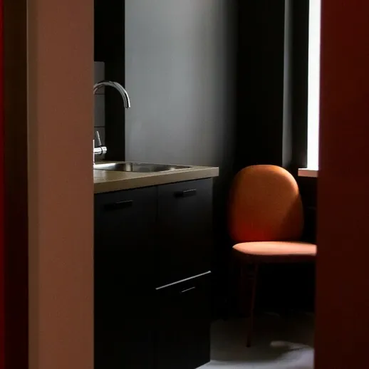 Уютный уголок в кухне с черными шкафами и оранжевым стулом у окна
