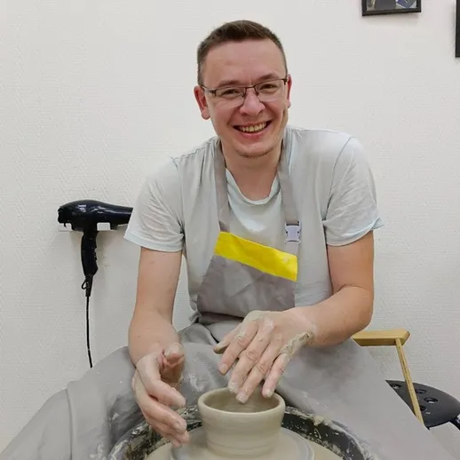 Мужчина работает с глиной на гончарном круге в мастерской во время занятия по керамике