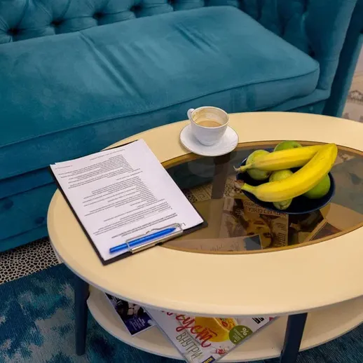 На журнальном столике в комнате синий диван, фрукты и документы, созданные для уютного отдыха и работы