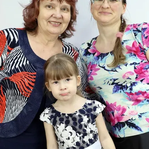 Счастливые три поколения: женщина, мама и дочь в нарядной одежде на фоне светлой стены