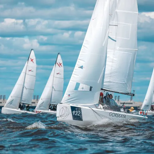 Регата на море, парусные лодки плывут к горизонту под облачным небом в ясный день