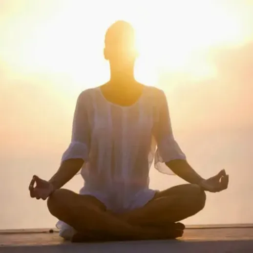 Женщина медитирует на берегу моря на закате, наслаждаясь спокойствием и умиротворением