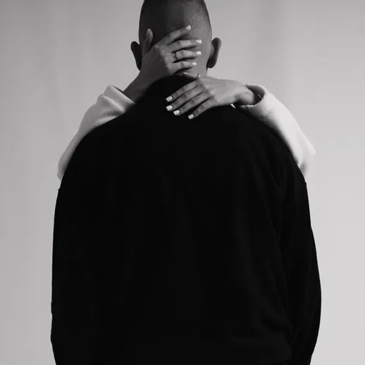 Объятия пары на фоне нейтральной стены в черно-белом цвете, символизирующие близость и доверие