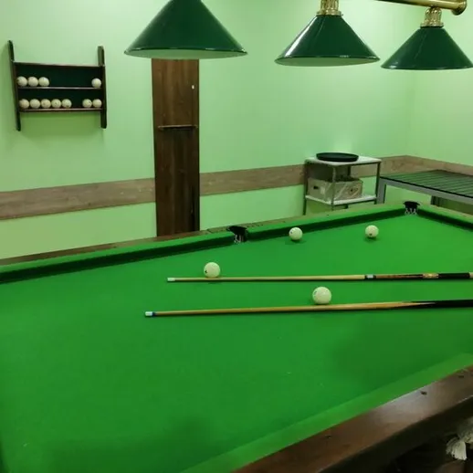 Игровой процесс на бильярдном столе в уютной комнате с зелеными стенами