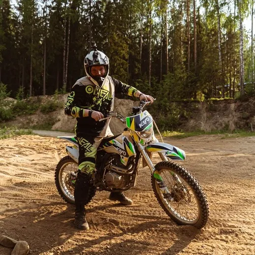 Мотоциклист в защитной экипировке на спортивном байке в лесной местности в летний день