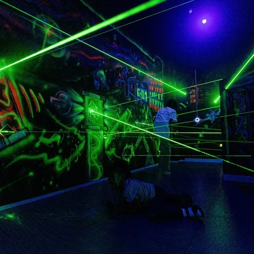 Игра с лазерами в темной комнате с неоновыми элементами в развлекательном центре