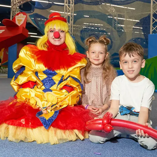 Восторженные дети веселятся с клоуном в игровом центре для семьи