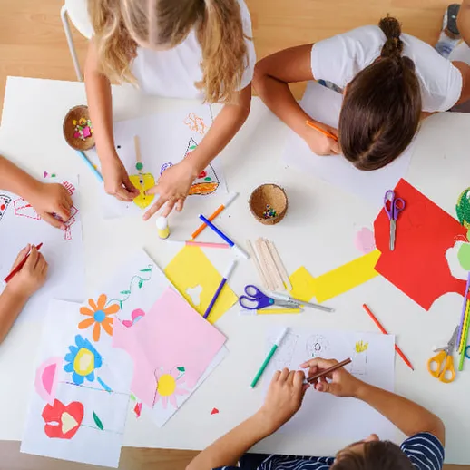 Дети занимаются творчеством, создавая поделки из бумаги в светлом помещении