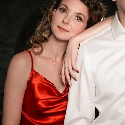 Пара в вечернем наряде на фоне темного интерьера, девушка в красном платье и мужчина в белой рубашке