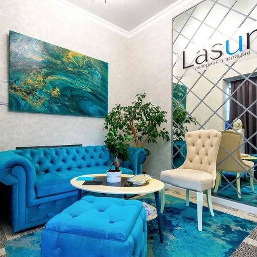 Современный интерьер уютного салона красоты с голубыми диванами и зеркалом в центре Москвы