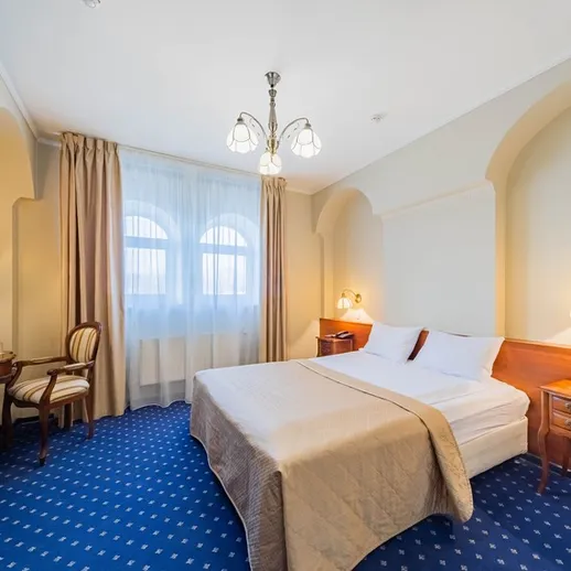 Уютный номер в отеле с двуспальной кроватью, современным интерьером и уютной обстановкой, освещенный естественным светом