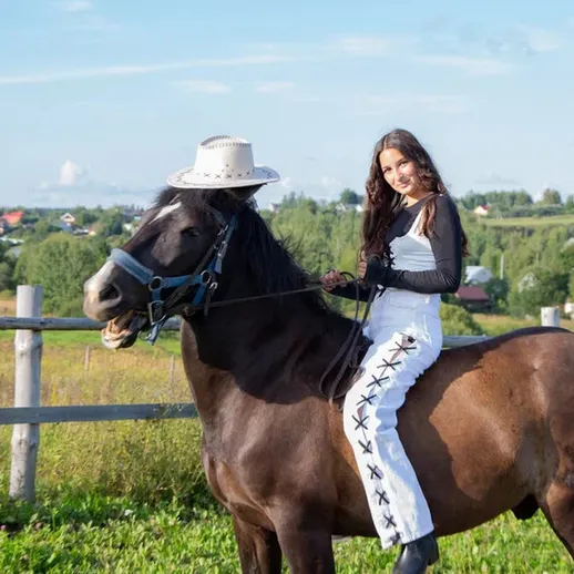 Девушка в белом одеянии едет на коне по живописному ландшафту летом в деревне