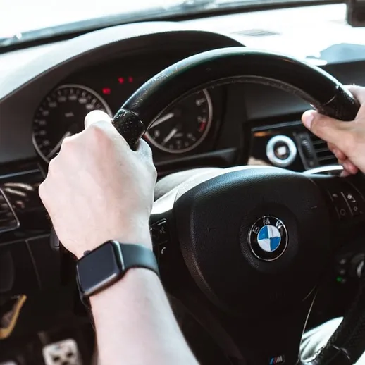 Водитель управляет автомобилем BMW, наслаждаясь поездкой по открытому шоссе в солнечный день