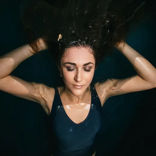 Красивый момент под водой: девушка с длинными волосами наслаждается плаванием в бассейне