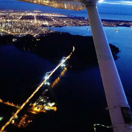 Ночной вид на город с высоты птичьего полета, огни метрополии и воды окружающего побережья