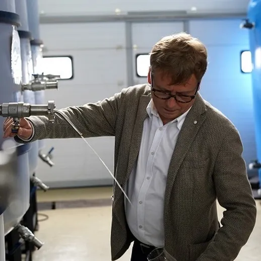 Человек в костюме контролирует процесс разлива напитка на винодельне в солнечный день