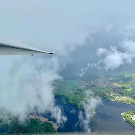 Полет над зелеными ландшафтами и водоемами в облачный день