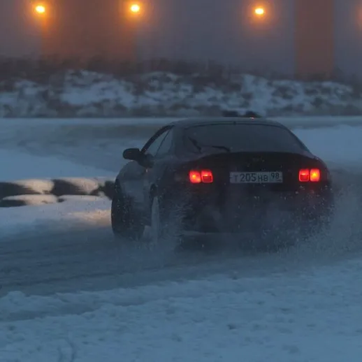 Зимние гонки на автомобиле по заснеженной трассе в холодное утро с туманом