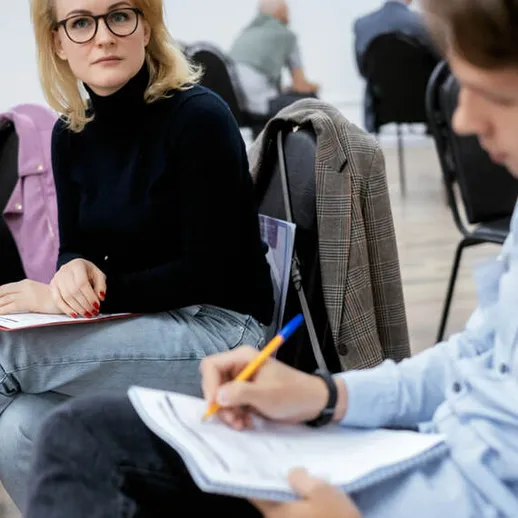 Женщина в очках внимательно слушает коллегу на деловой встрече в конференц-зале