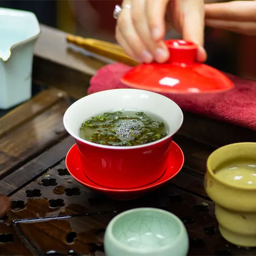 Заваривание зеленого чая в традиционном чайном мире с красной чашкой и узорчатым подносом