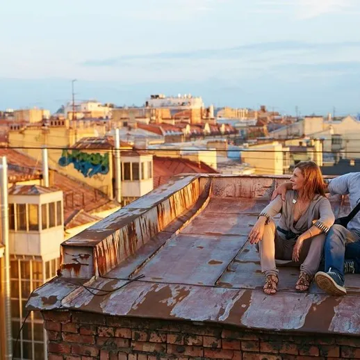 Пара наслаждается закатом на крыше дома в городе с живописными видами на архитектуру и улицы